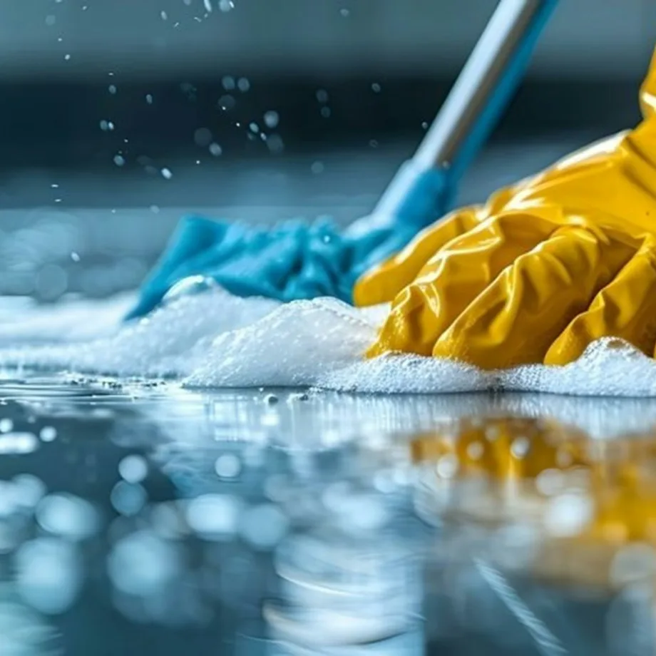 Gloved hand scrubbing a wet floor with a cloth