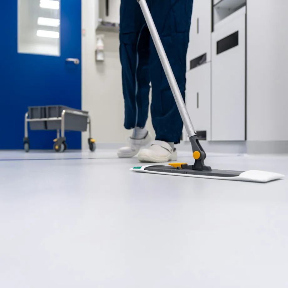 Cleaner mopping a spotless white corridor floor